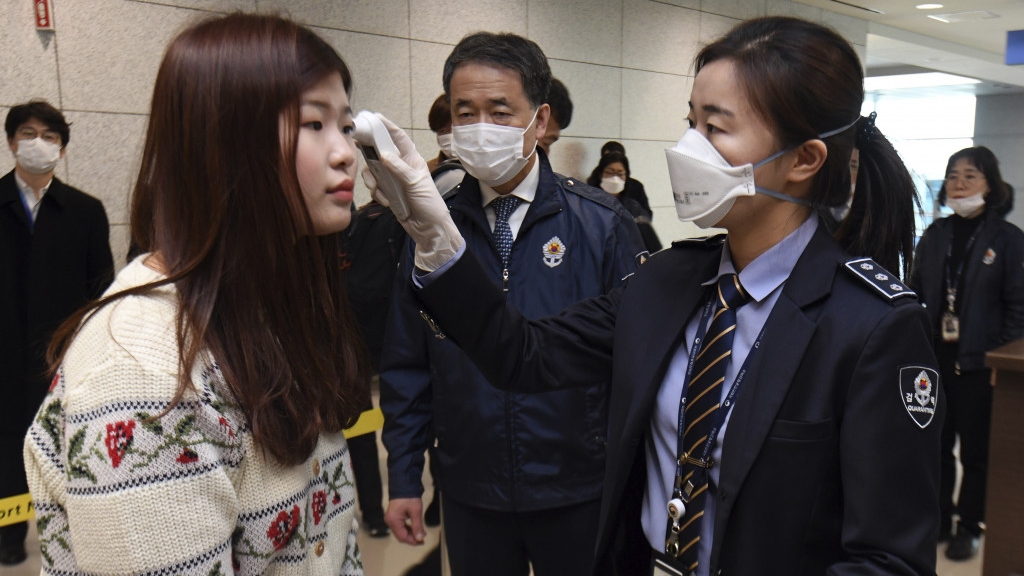 韩国仁川国际机场工作人员对旅客进行检测。（图/美联社）