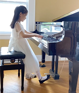 8歲的Lucy正在彈奏鋼琴（圖片來源：大紀元）