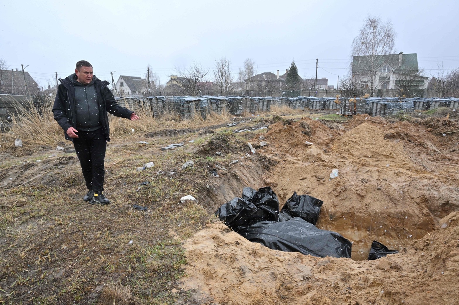 2022 年 4 月 3 日，一名男子在烏克蘭首都基輔西北部 Bucha 鎮的一個亂葬坑上做手勢。 - 在附近發現亂葬坑和“處決”平民後，烏克蘭和西方國家指責俄羅斯軍隊犯有戰爭罪 基輔，促使國際刑事法院宣誓採取行動。