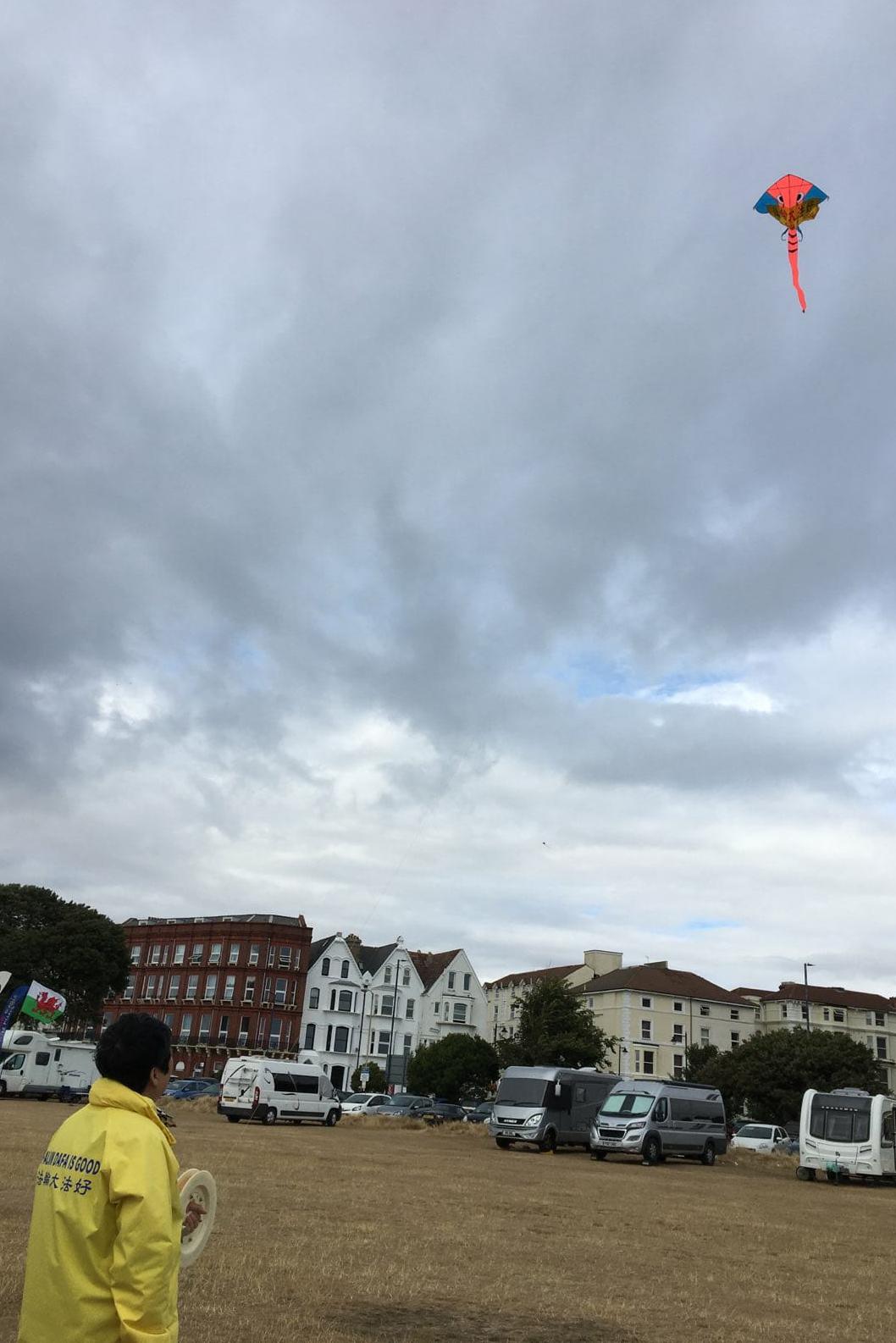 英國法輪功學員的風箏帶着金黃色橫幅也高高的飛在空中，橫幅上面的中文 &quot;法輪大法好&quot; 和英文翻譯: &quot;Falun Dafa is good&quot; 十分顯眼。（圖片來源：Sunny/英國）