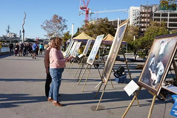 2022年10月29日，加州聖地亞哥法輪功學員在聖地亞哥港口公園舉行《真善忍畫展》，過往行人駐足觀看並簽名支持法輪功發迫害和“解體中共”（圖片來源：大紀元）