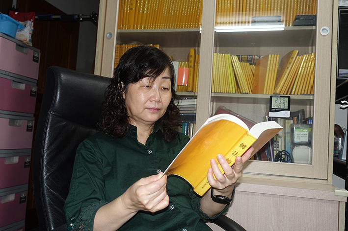 許美惠在家中閱讀《轉法輪》（圖片來源：明慧網）