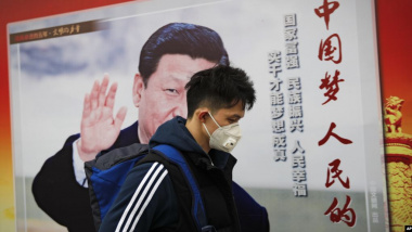 資料照：一名男子走過北京街頭習近平的宣傳畫。（AP）
